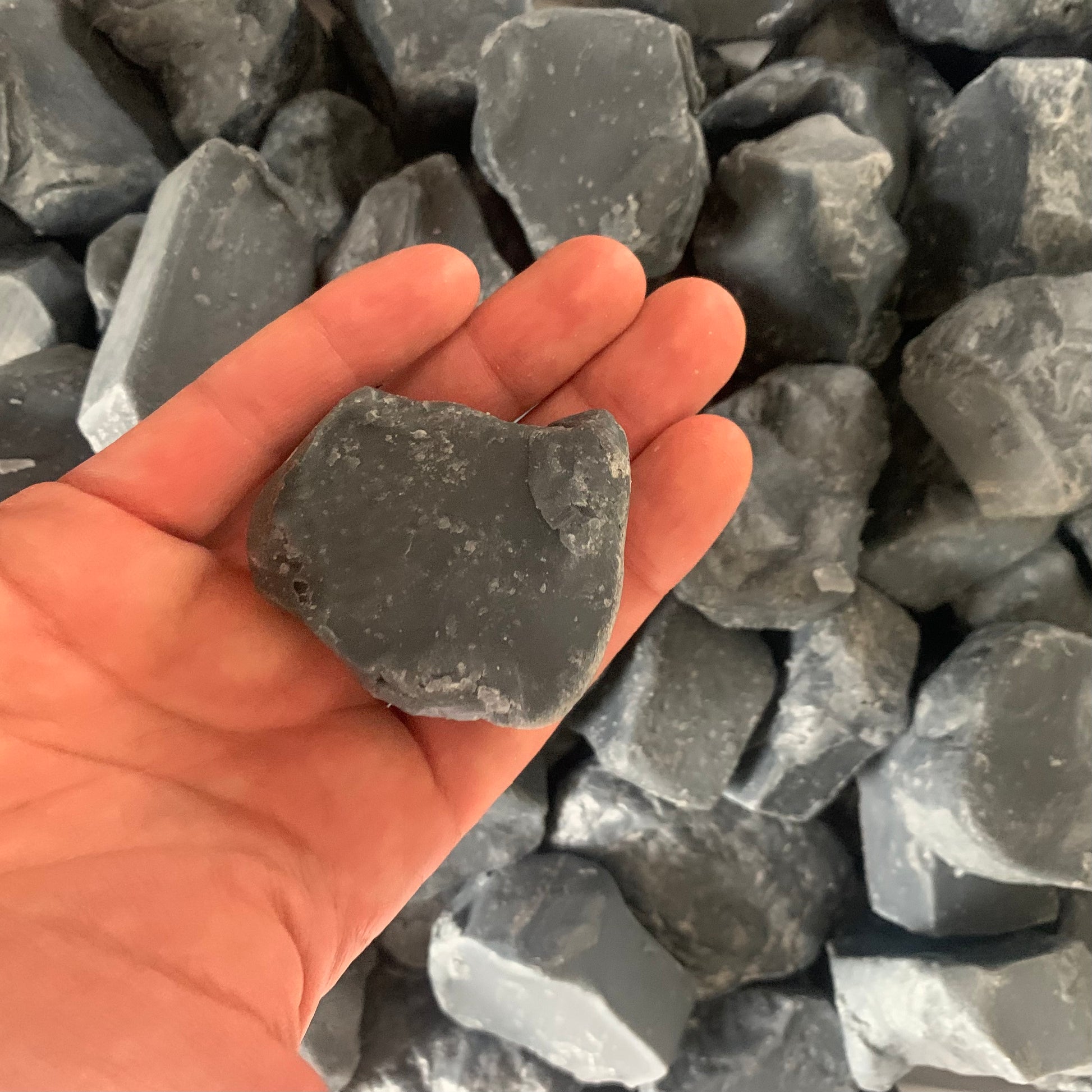 one piece of dark grey soap held in a hand for scale